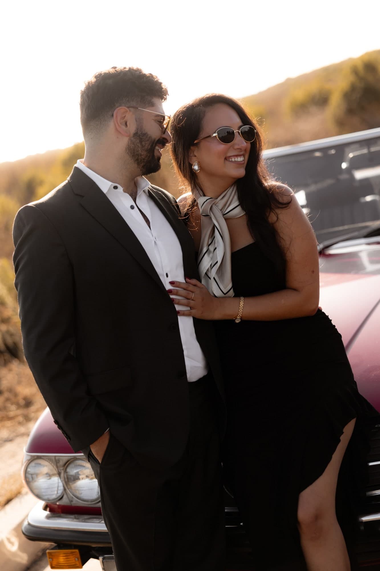 David and Joy laughing beside the convertible in golden-hour light